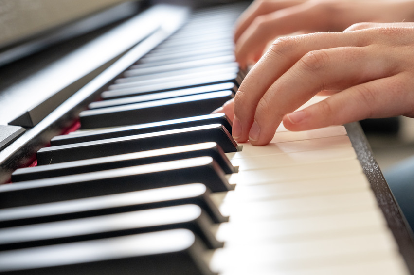 Närbild tagen på ett piano som en elev spelar på.
