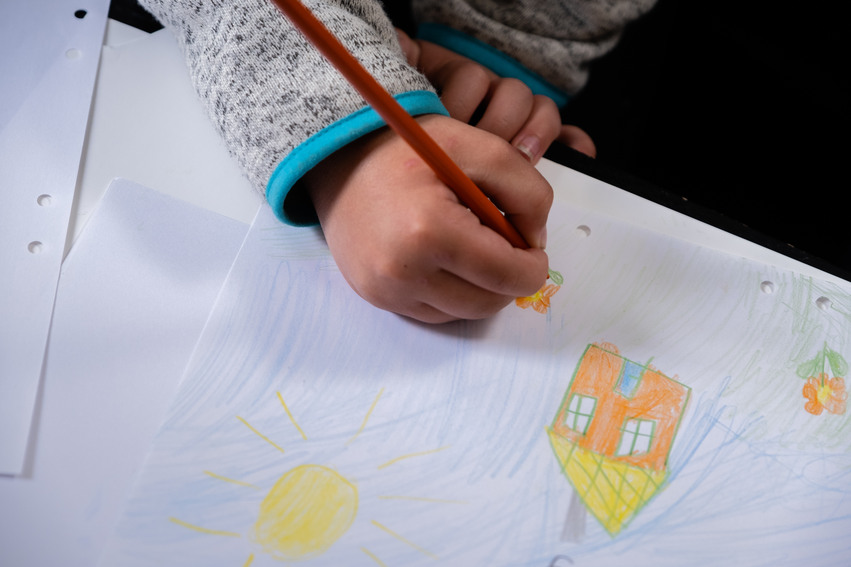 Ett barn ritar ett hus.