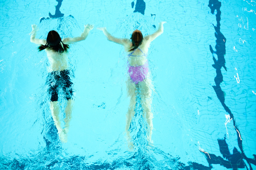 Bild på två unga personer som simmar i en bassäng