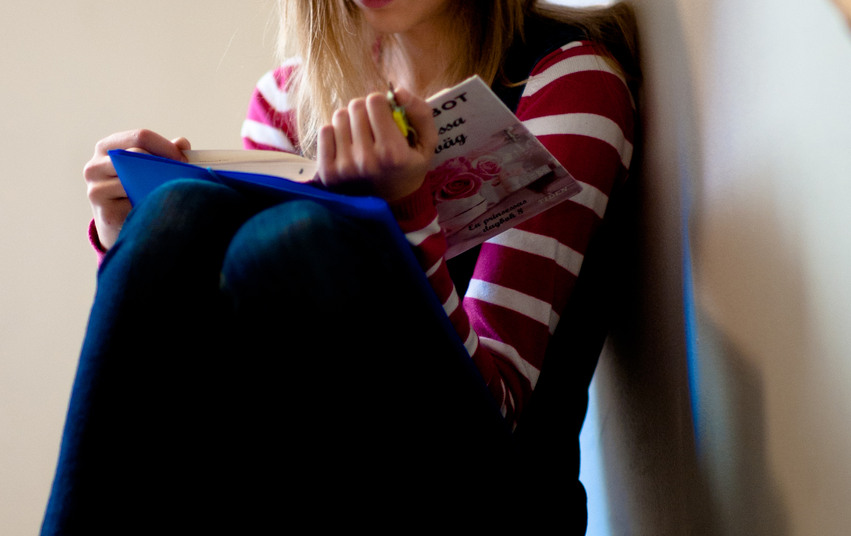 Flicka sitter i en trapp med en bok.
