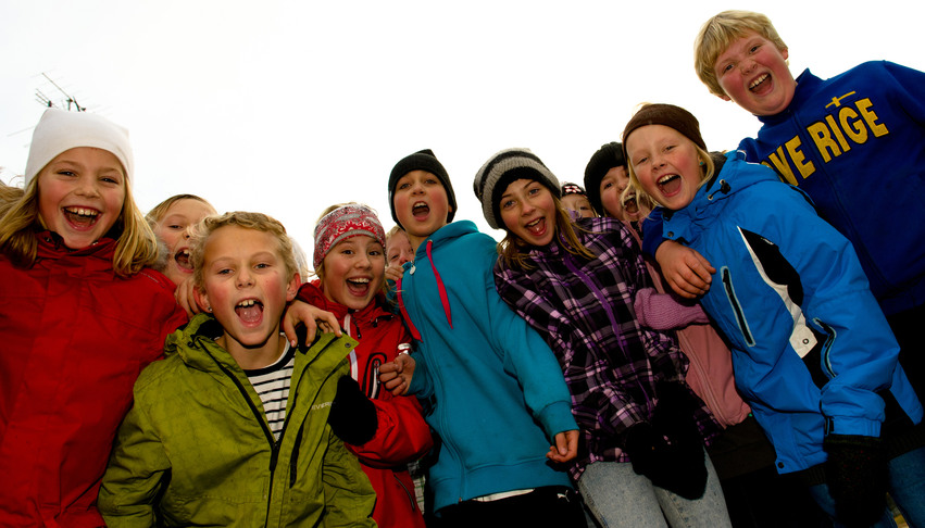 Närbild på flera grundskoleelever som står lutad över kameran och skrattar. Bilden är tagen underifrån.