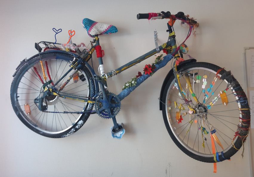 Bild på dekorerad och utsmyckad cykel upphängd på en vägg.