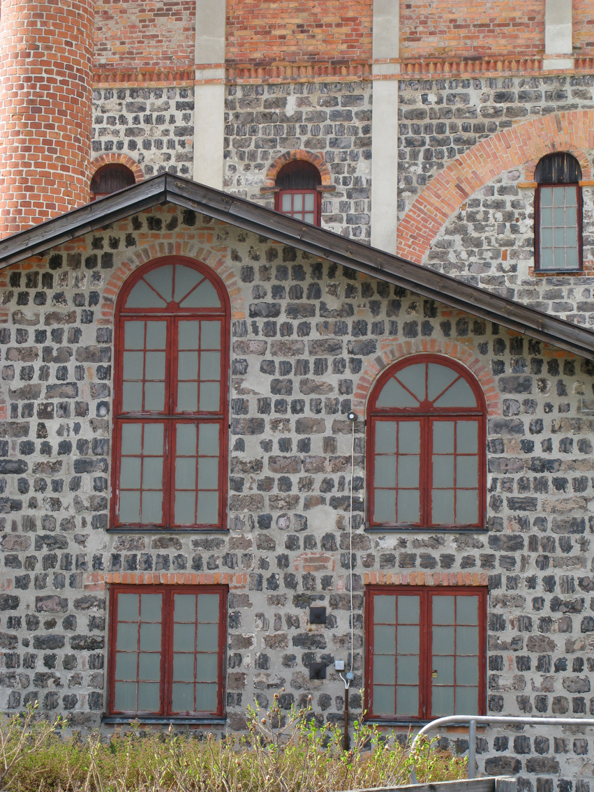 Hälsinglands museum. En stor gammal stenbyggnad med höga ovala fönster indelade i små rutor. Fönsterkarmarna är rödmålade.