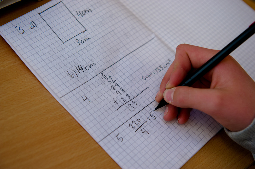Elev skriver matematik i ett skrivhäfte.