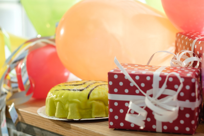En tårta bredvid ett paket och flera ballonger 