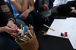 Vuxna och barn vid soffbord med pennor och papper
