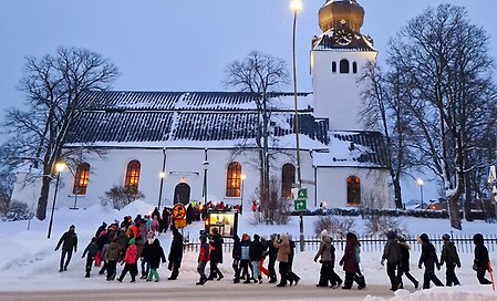 Skolelever går fackeltåg mot Jakobs kyrka i Hudiksvall.