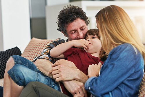 Familj i en soffa, två vuxna och ett barn