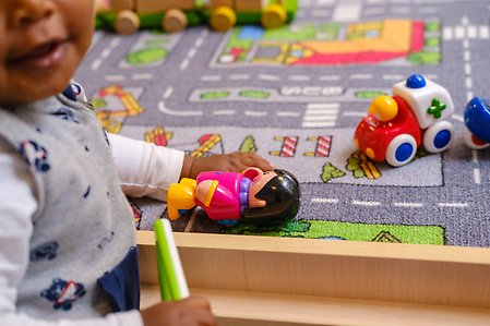 Ett barn leker med leksaker på en matta.